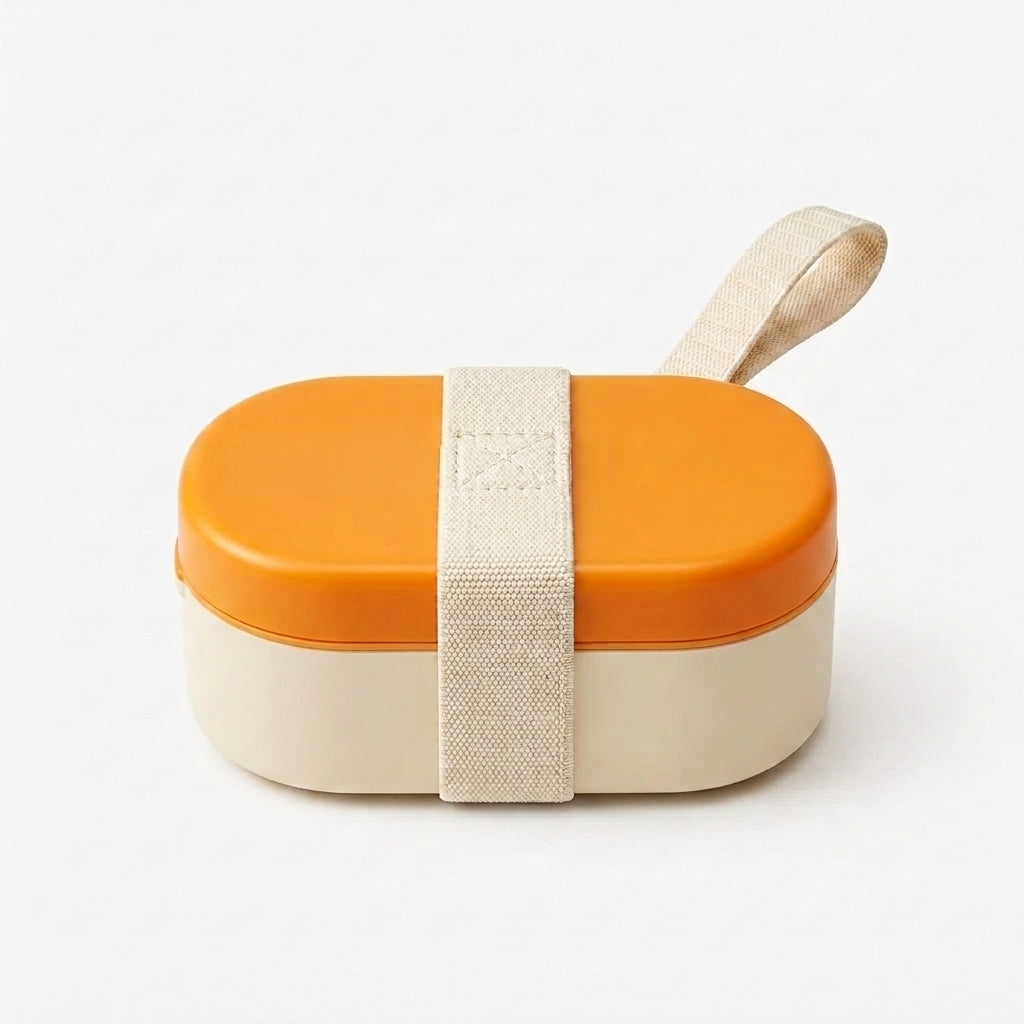 An oval-shaped pet lunch box with a bright orange top lid, a cream-colored bottom container, and a beige fabric strap wrapped around the front with a matching loop handle.